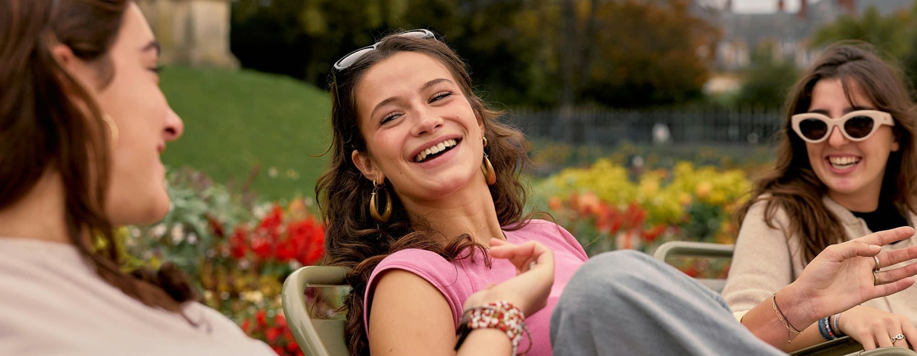 Three women sitting in chairs next to a garden and laughing.